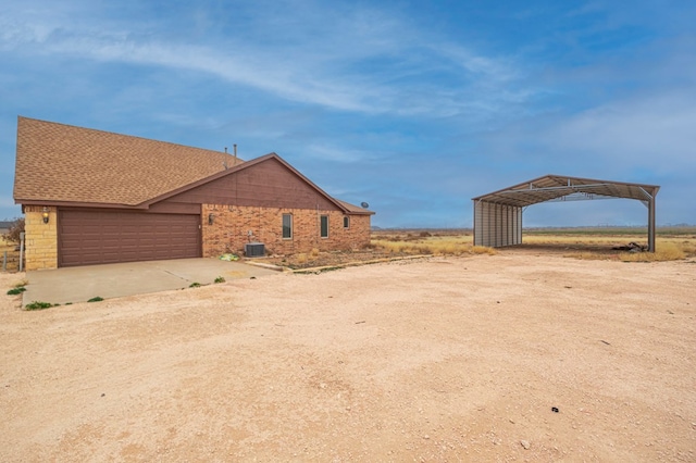 view of yard featuring a carport, a garage, and central AC unit