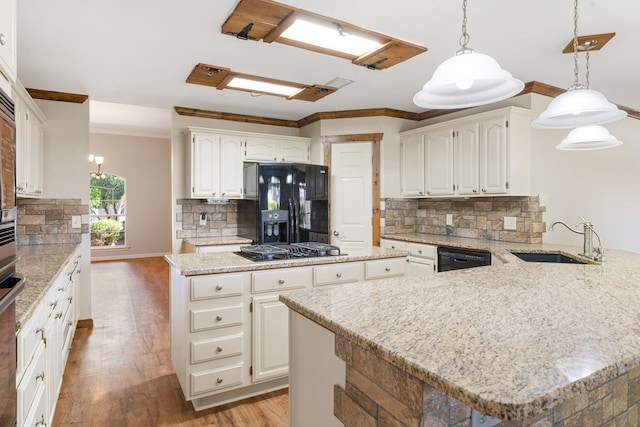 kitchen with sink, hanging light fixtures, tasteful backsplash, white cabinets, and black appliances