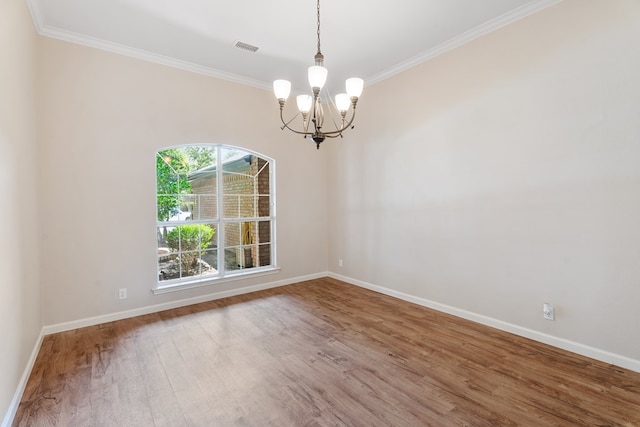 empty room with hardwood / wood-style flooring, crown molding, and a notable chandelier