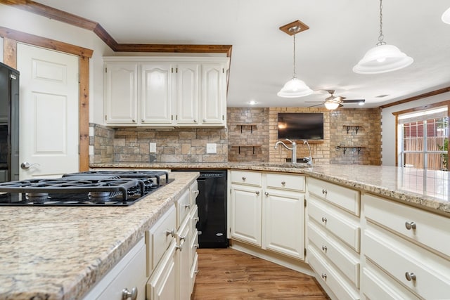 kitchen featuring sink, tasteful backsplash, light hardwood / wood-style flooring, pendant lighting, and black appliances