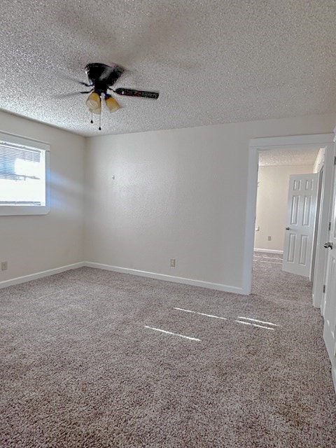 carpeted spare room featuring ceiling fan and a textured ceiling