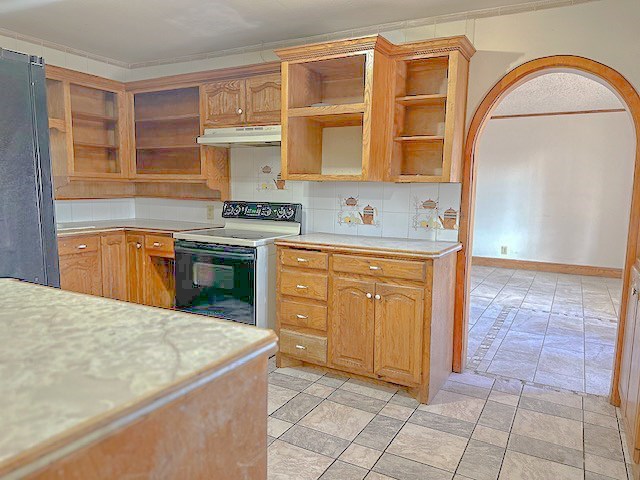 kitchen with white range with electric cooktop, refrigerator, ornamental molding, and backsplash