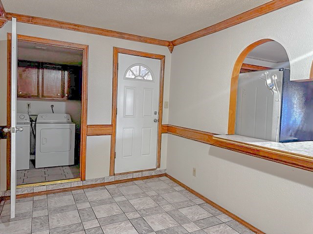 entryway featuring a textured ceiling, washing machine and dryer, and ornamental molding