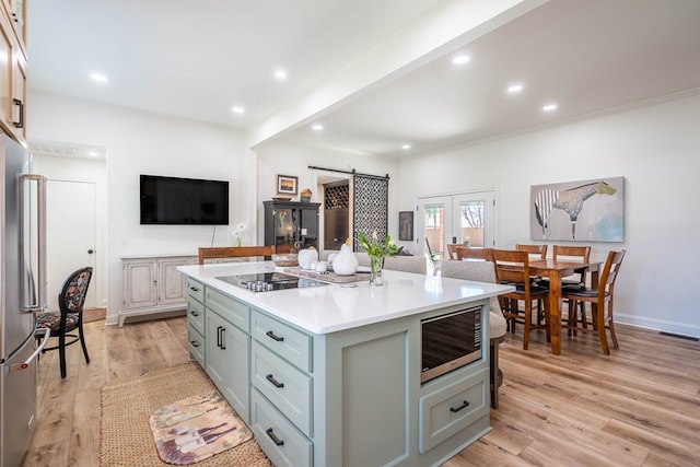 2223 S 2nd Pl, Lamesa, TX 79331 - kitchen with black electric stovetop, a barn door, light wood-style floors, built in microwave, and freestanding refrigerator