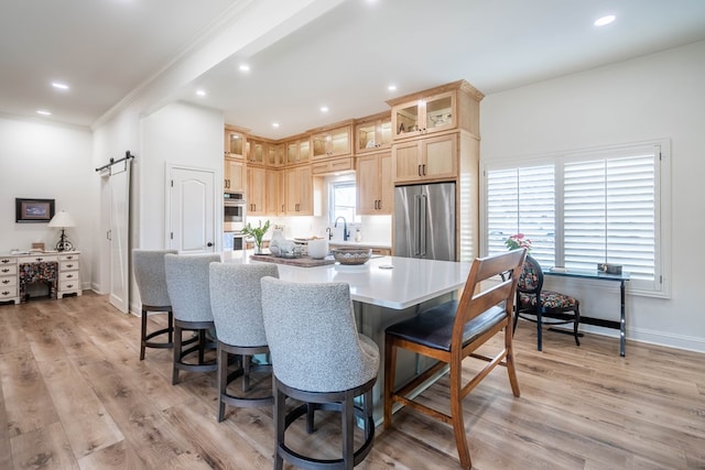 2223 S 2nd Pl, Lamesa, TX 79331 - kitchen with a sink, a barn door, light brown cabinetry, appliances with stainless steel finishes, and light wood-type flooring