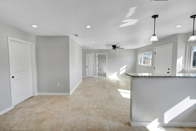 kitchen featuring ceiling fan, stone counters, and pendant lighting