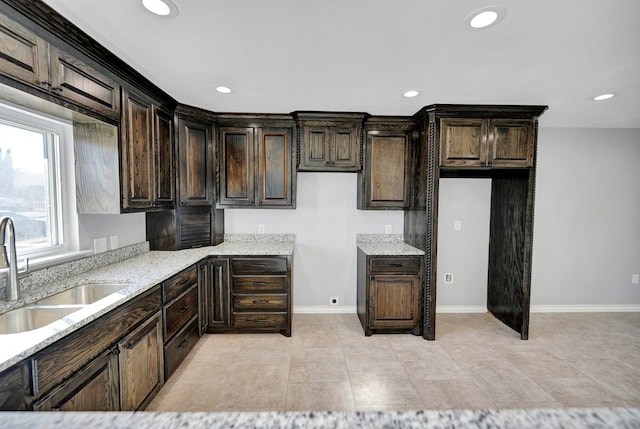 kitchen featuring light stone countertops, sink, and dark brown cabinetry