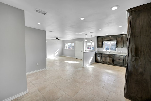 kitchen featuring ceiling fan, light tile patterned flooring, pendant lighting, and dark brown cabinets