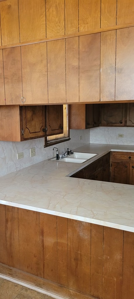 kitchen featuring light stone countertops, tasteful backsplash, and sink