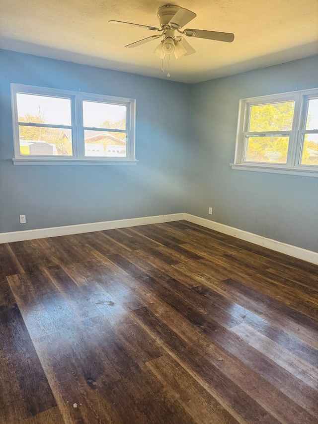 empty room featuring a healthy amount of sunlight, a ceiling fan, baseboards, and wood finished floors