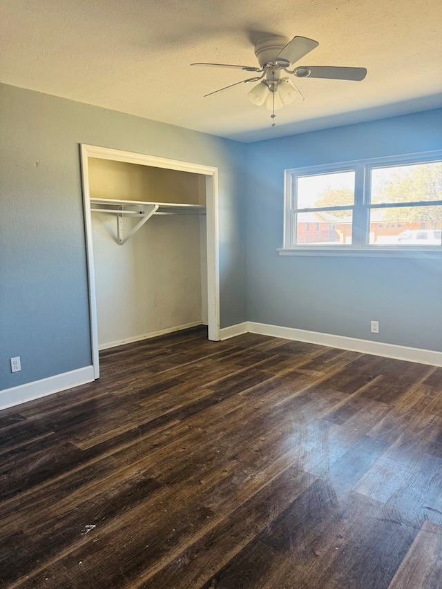 unfurnished bedroom with ceiling fan, a closet, baseboards, and dark wood-type flooring