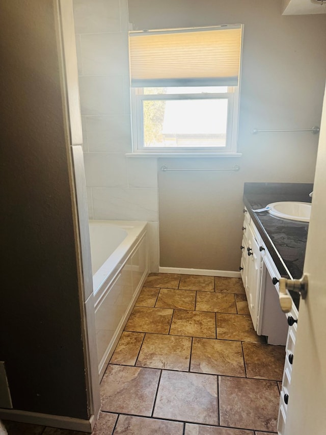 bathroom with a tub to relax in, vanity, and baseboards