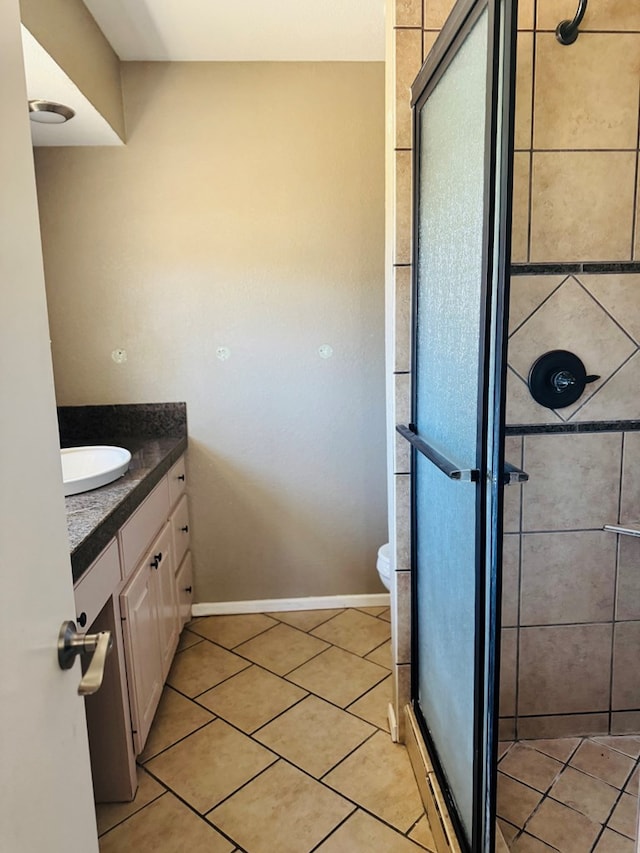 bathroom with baseboards, toilet, tile patterned flooring, vanity, and a shower stall