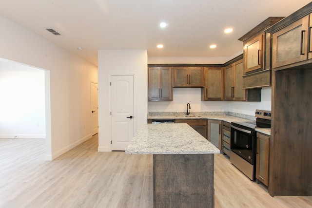 1202 Main St, Big Spring, TX 79720 - kitchen with electric stove, light wood-type flooring, a center island, light stone countertops, and baseboards