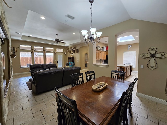 dining space with stone tile floors, arched walkways, baseboards, and ceiling fan with notable chandelier