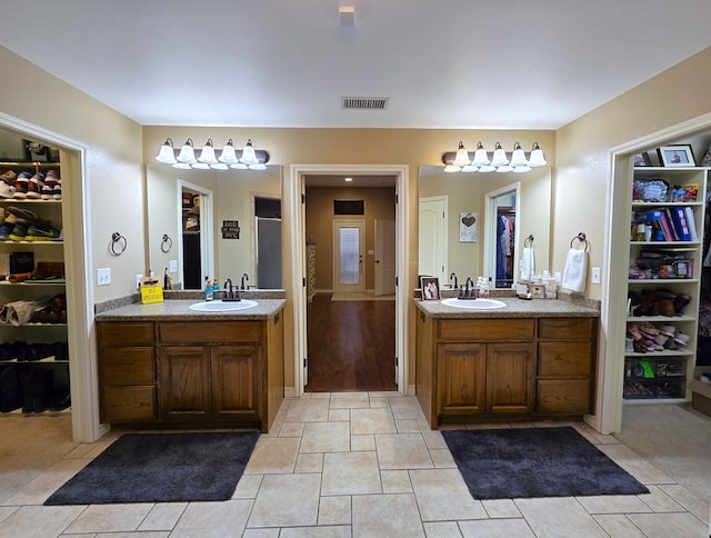 bathroom with visible vents, a sink, and two vanities