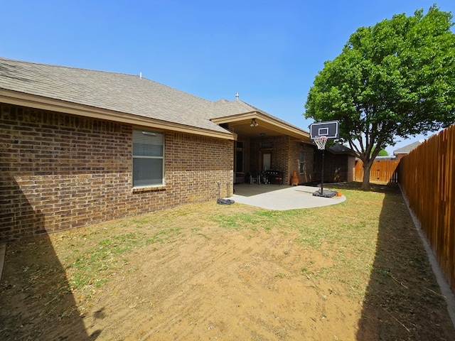 back of house with brick siding, a fenced backyard, a patio area, and a shingled roof