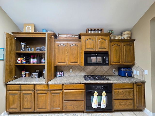 kitchen with brown cabinetry, open shelves, light countertops, backsplash, and black appliances