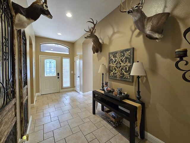 entrance foyer featuring stone finish flooring, arched walkways, baseboards, and recessed lighting