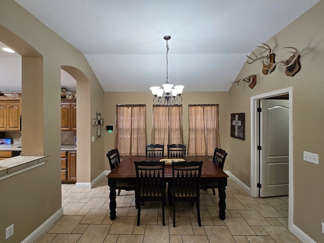 dining area with arched walkways, plenty of natural light, vaulted ceiling, and a chandelier