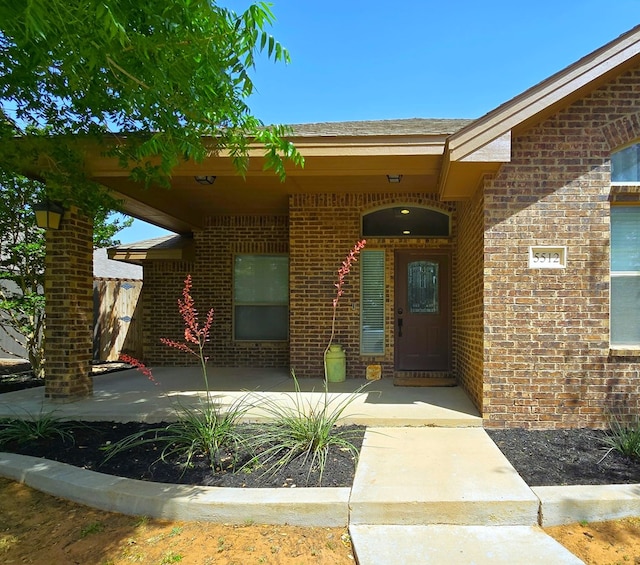 entrance to property featuring brick siding and a patio