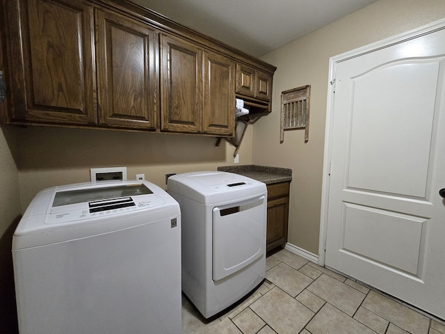 laundry room with washing machine and clothes dryer, light tile patterned floors, and cabinet space