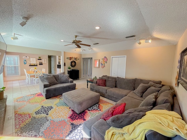 tiled living room featuring ceiling fan, rail lighting, and a textured ceiling