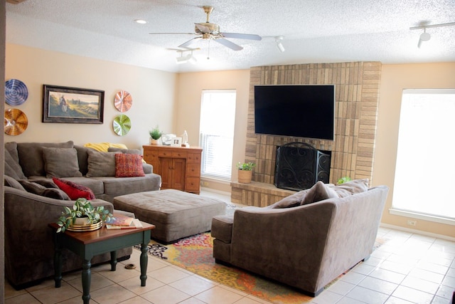 living room with a wealth of natural light, a textured ceiling, a fireplace, and light tile patterned floors