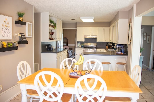 kitchen featuring stainless steel gas range, sink, kitchen peninsula, and light tile patterned floors