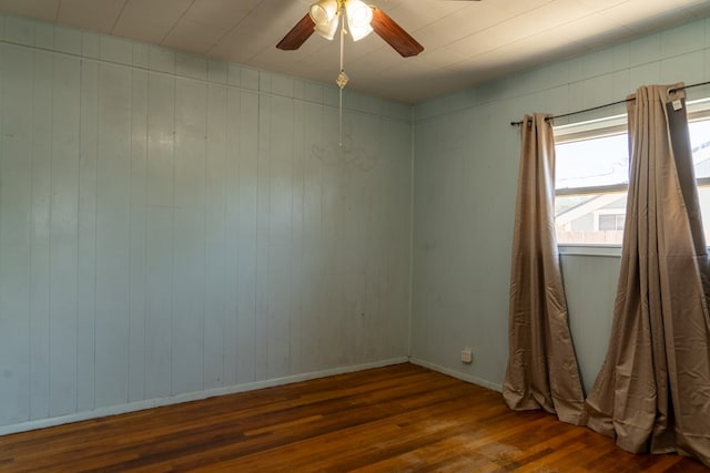 spare room featuring wooden walls, dark hardwood / wood-style flooring, and ceiling fan