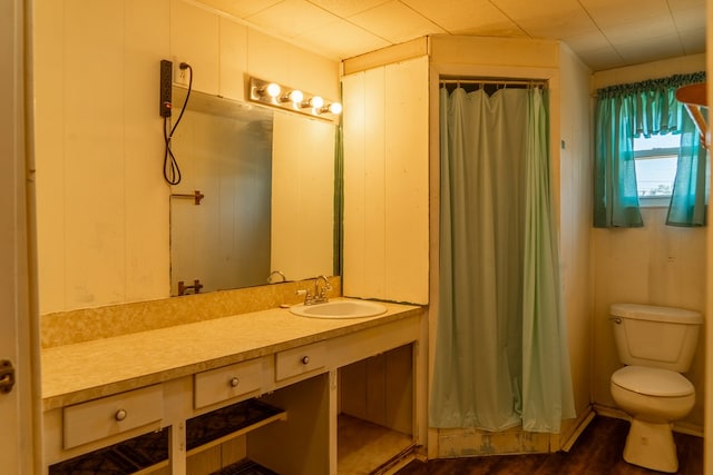 bathroom featuring walk in shower, wood walls, wood-type flooring, toilet, and vanity