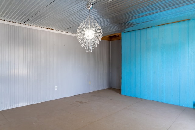 spare room with a notable chandelier and concrete floors