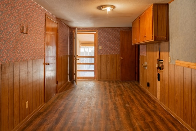 corridor featuring wooden walls, dark hardwood / wood-style flooring, and a textured ceiling