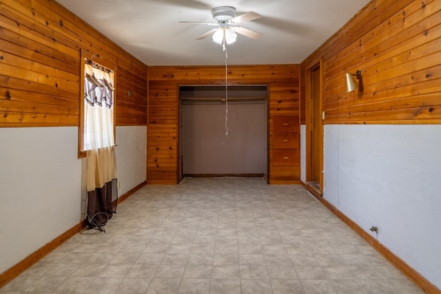 unfurnished bedroom with wooden walls, a closet, and ceiling fan