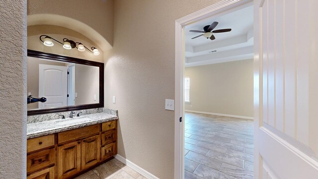 2894 SE 5001, Andrews, TX 79714 - bathroom with vanity, a textured wall, a raised ceiling, baseboards, and ceiling fan