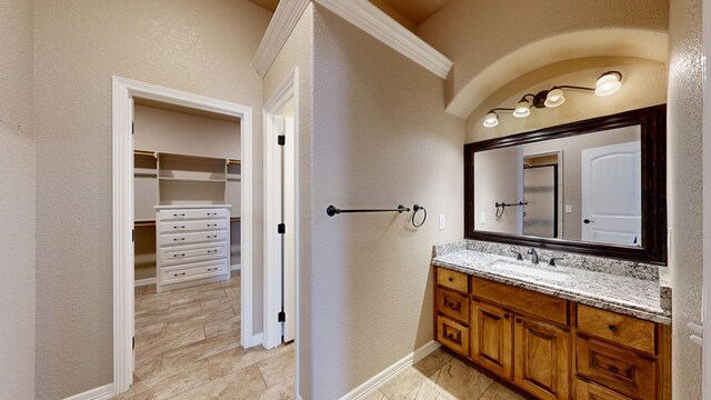 2894 SE 5001, Andrews, TX 79714 - bathroom with vanity, a walk in closet, a textured wall, and baseboards