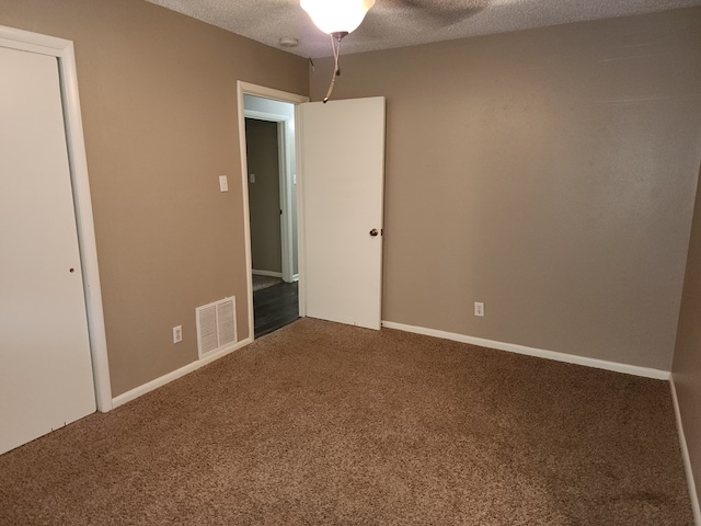 carpeted empty room with ceiling fan and a textured ceiling