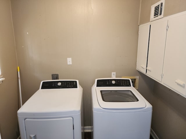 clothes washing area featuring cabinets and independent washer and dryer