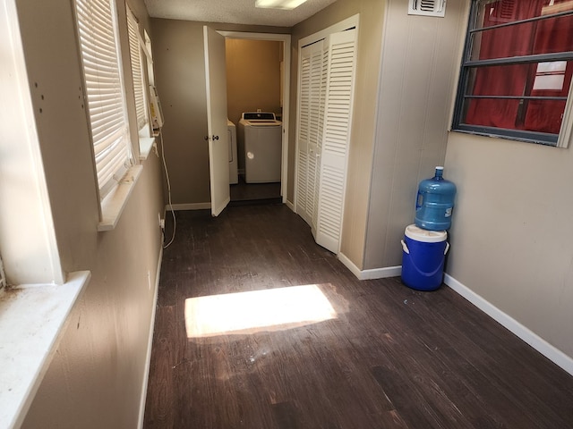 hallway with a textured ceiling, washer / clothes dryer, and dark hardwood / wood-style floors