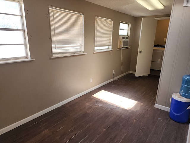 spare room featuring cooling unit, dark wood-type flooring, a textured ceiling, and washer / dryer