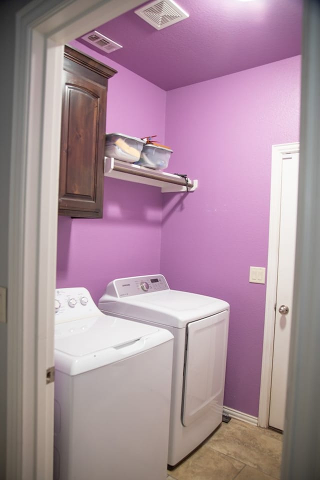 laundry area featuring cabinets, independent washer and dryer, and light tile patterned floors