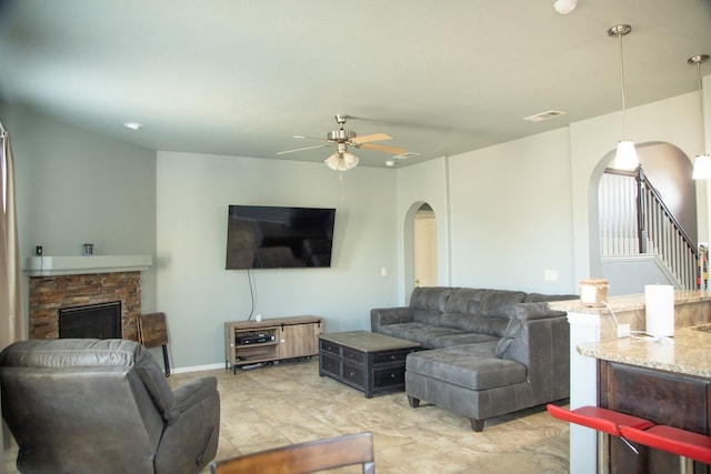 living room with ceiling fan and a fireplace