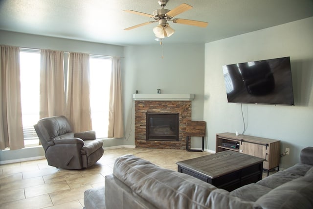 living room with light tile patterned floors, a stone fireplace, ceiling fan, and a healthy amount of sunlight