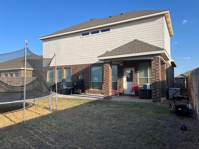 rear view of house featuring a lawn, a trampoline, and a patio