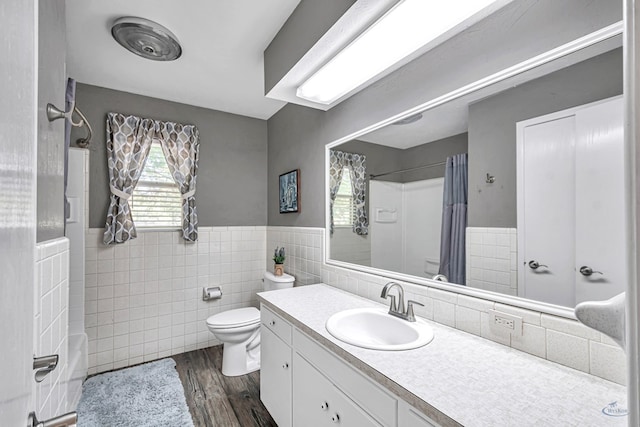 2512 Sinclair Ave, Midland, TX 79705 - full bath featuring toilet, tile walls, wood finished floors, vanity, and wainscoting