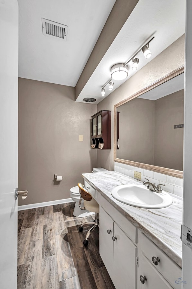 2512 Sinclair Ave, Midland, TX 79705 - bathroom featuring vanity, wood finished floors, toilet, baseboards, and rail lighting