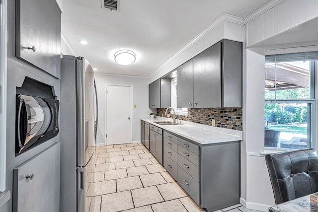 2512 Sinclair Ave, Midland, TX 79705 - kitchen featuring gray cabinets, freestanding refrigerator, light countertops, ornamental molding, and tasteful backsplash