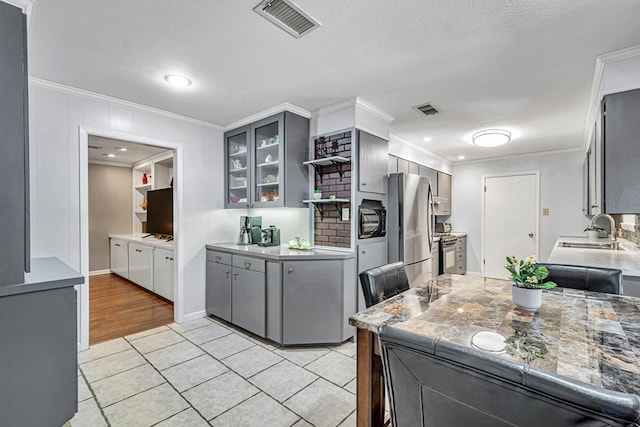 2512 Sinclair Ave, Midland, TX 79705 - kitchen with gray cabinetry, ornamental molding, stainless steel appliances, a sink, and light tile patterned floors