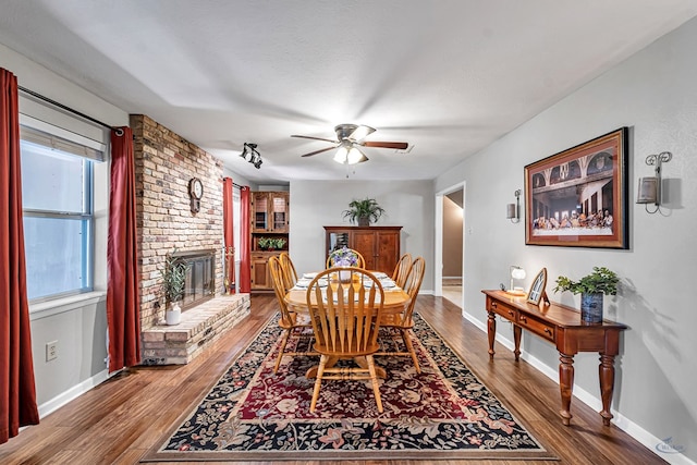 2512 Sinclair Ave, Midland, TX 79705 - dining area with wood finished floors, a ceiling fan, a brick fireplace, and baseboards