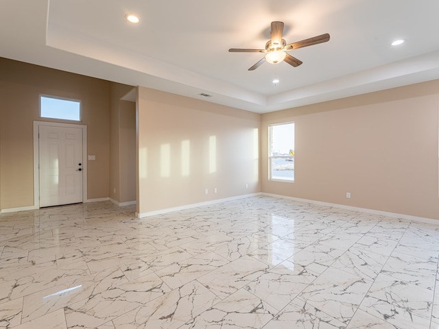 unfurnished room featuring a raised ceiling and ceiling fan